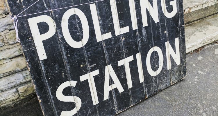 Black board painted with white letting stating "Polling Station".